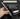 A hand holds a compact gray pen-style tool with a metal tip against a dark background, with marketing text reading 'COMPACT PEN DESIGN' and additional copy about slim aluminum alloy housing for repairing electronics. A small white-and-gray accessory case is shown at lower right.