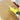 Yellow box cutter cutting through cardboard with a blurred red and white background.