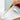Person using a yellow utility knife to cut white paper on a light blue background.