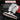 A close-up of an angle grinder with a red handle and silver metal housing, shown against a dark background. White text at the top reads 'STRONG GRIP,' and a semi-transparent text box on the left lists available backing plate sizes from 3" to 7".