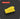 A bright yellow rectangular foam-like block with rounded top edges, shown on a dark gray background with subtle concentric circular lines. A red label at top left reads “SQUARE 2.