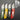 Four colorful pocket knives with different handle colors on a dark background