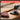 A cordless tri-tip sanding attachment shown on a wooden surface with sanding discs attached, plus marketing text that reads 'PREMIUM SANDING POWER' and 'INDUSTRIAL-GRADE CHROME AND PU BACKING BUILT TO SURVIVE HIGH-VIBRATION SANDING.'.