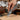 Hand holding a knife, cutting through leather with a workshop background.