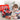 Young boy sitting on a carpet, playing with a red and black toy toolbox filled with various toy tools in a home setting.