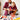 Father and son smiling while using a red toy drill together at a workbench, surrounded by toy tools including hammer, pliers, screwdrivers, and plastic bolts.
