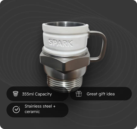 A ceramic and stainless steel mug with a threaded base, featuring a white ceramic upper section with the brand name 'SPARK' embossed, a metallic hex nut design, and a stainless steel handle. Three black feature badges at the bottom highlight its 355ml capacity, stainless steel and ceramic construction, and make it a great gift idea, all set against a dark gray background with concentric circle patterns.